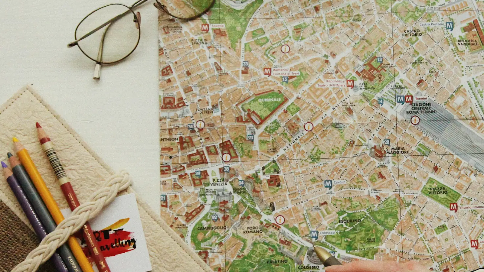 Reiseplanung am Schreibtisch: Stadtplan, Brille, Buntstifte und Notizbuch für die Vorbereitung einer Reise